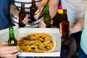 Mid section of friends having bottle of beer and pizza in party at bar-1