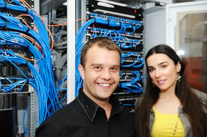 Two administrators, male and female, at server room